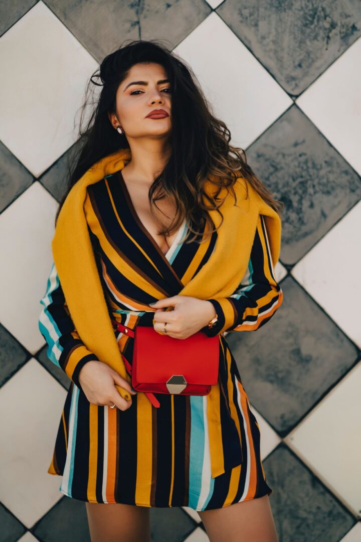 A woman in a striped dress holding onto a red purse