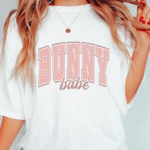 A person wearing a white shirt with bunny babe written on it