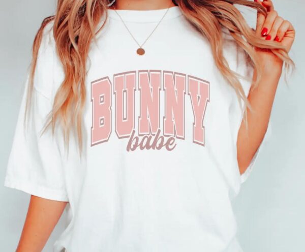 A person wearing a white shirt with bunny babe written on it