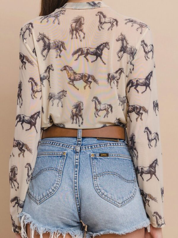 A woman wearing high waisted jeans and a horse print shirt.